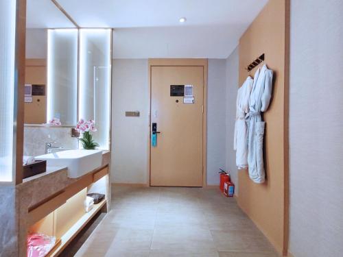 广州柏高酒店(广州南站番禺长隆店)的浴室配有盥洗盆、镜子和浴袍