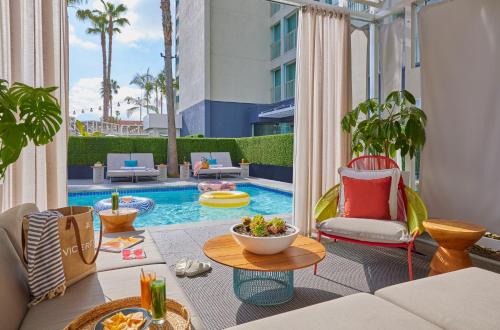 洛杉矶圣莫尼卡总督酒店的庭院设有带椅子和桌子的游泳池。