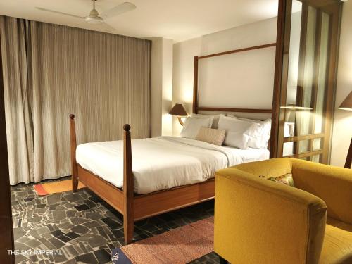 拉杰果德The Sky Imperial Aarivaa Luxury HomeStay的一间卧室配有一张床、一张沙发和一把椅子