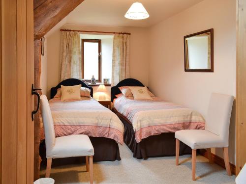 Aber-Brân查尔格罗夫度假屋的一间卧室配有两张床、一把椅子和镜子