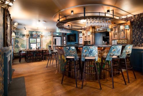 格拉斯米尔The Swan at Grasmere- The Inn Collection Group的餐厅内带蓝色椅子的酒吧