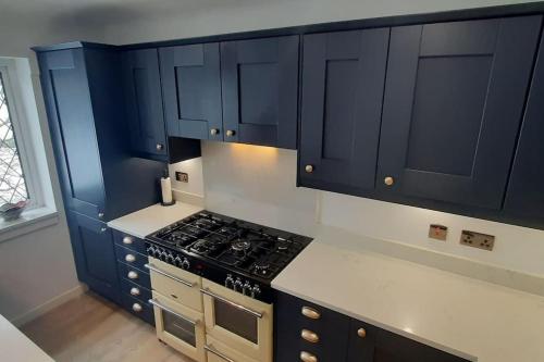 西柯比GOLF OPEN HOYLAKE Bungalow In West Kirby的厨房配有蓝色橱柜和炉灶烤箱。