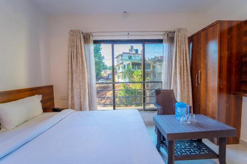 马哈巴莱斯赫瓦尔Dhimahi Residency的一间卧室配有一张床、一张桌子和一个窗户。