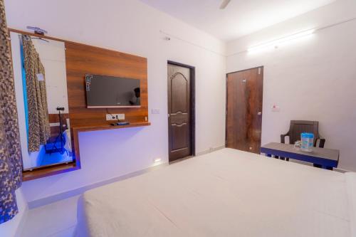 马哈巴莱斯赫瓦尔Dhimahi Residency的一间设有床铺和墙上电视的房间