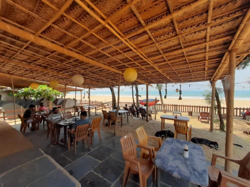 戈卡尔纳Trippr Gokarna - Beach Hostel的海滩上的餐厅,有人坐在桌子旁