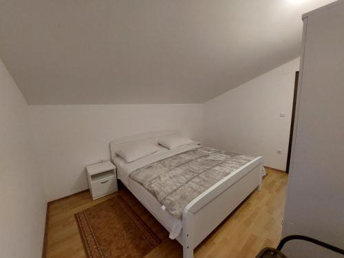 格雷巴蒂卡Apartman Ema的一间白色的小卧室,配有床和床头柜