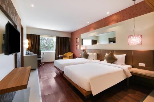 浦那7 Apple Hotel Pimpri Pune的酒店客房,设有两张床和镜子