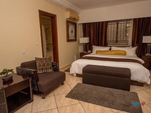 阿克拉Orchid Hotel的一间卧室配有一张床、一张沙发和一把椅子