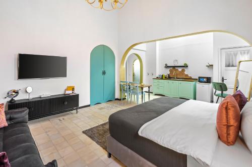 贝尔谢巴מלון הליוס בוטיק מרשת מלונות לה פינקה的一间卧室配有一张床、一张沙发和一台电视。
