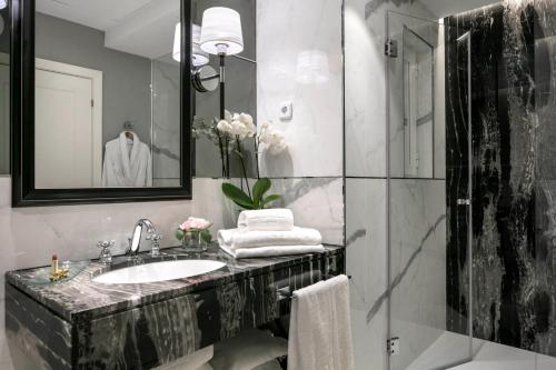 马德里艾普拉杜尔酒店的浴室配有盥洗盆和带镜子的淋浴