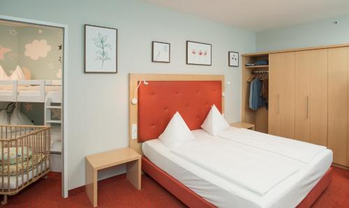 路茨曼贝格Hotel Sonnenpark & Therme included - auch am An- & Abreisetag!的一间卧室配有一张大床和一张婴儿床。