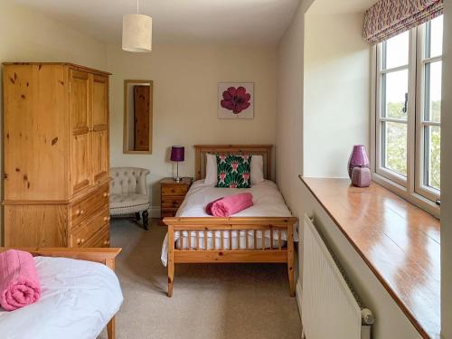 Menheniot霍利韦尔谷仓度假屋的一间卧室配有带粉红色枕头的床。