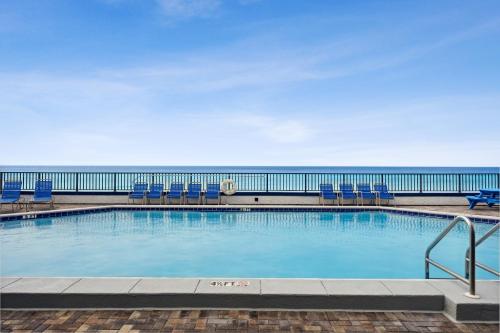 巴拿马城海滩AquaVista Beach Resort by Panhandle Getaways的一个带椅子的游泳池,背景是大海