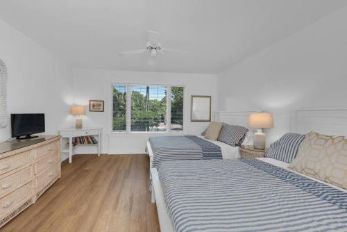 棕榈岛Seagrove Villa 5B - Oceanside Villa in the Trees的一间白色卧室,配有两张床和电视