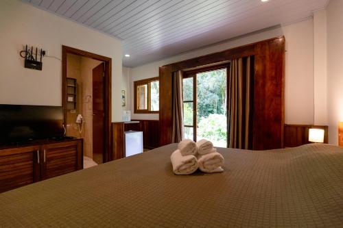 坎波斯杜若尔当Surya-Pan Hotel Refúgio的一间卧室配有带毛巾的床