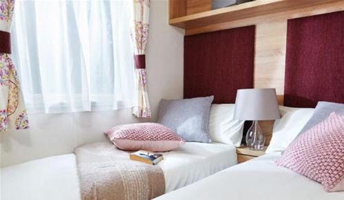 佩恩顿Hoburne Devon Bay Stunning 3 bed static caravan with full decking的一间卧室配有两张床和一张带台灯的桌子