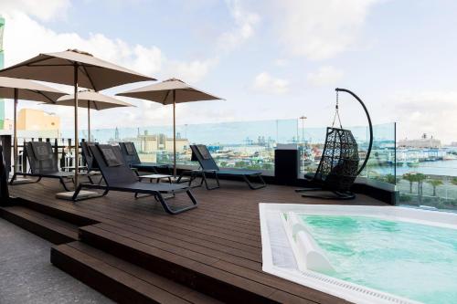 大加那利岛拉斯帕尔马斯Sercotel Puerto de la Luz的屋顶甲板设有游泳池、椅子和遮阳伞