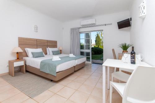 拉戈斯Atalaia Sol Aparthotel - tennis & heated pool in winter的一间卧室配有一张床、一张桌子和一张书桌