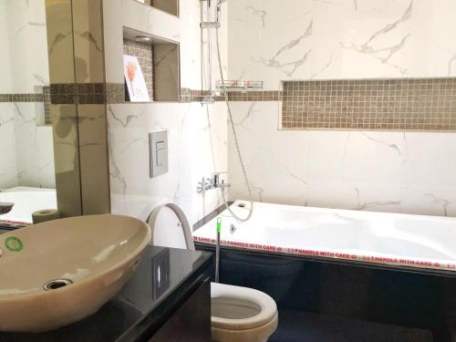 新德里Avatar Living@ Greater Kailash 2的浴室配有盥洗盆、卫生间和浴缸。