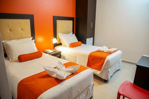 特鲁希略Hotel Killari Trujillo的酒店客房,设有两张带橙色墙壁的床
