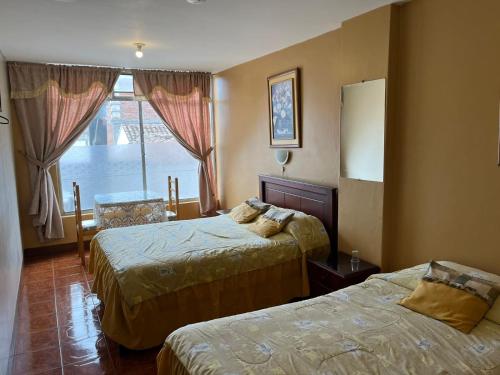 拉塔昆加Hotel Cotopaxi的酒店客房设有两张床和窗户。