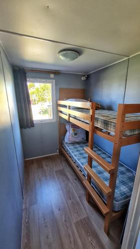 耶尔Mobil home 6 personnes camping 4* Les Pins Maritimes的小房间设有两张双层床和窗户