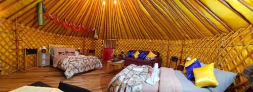 乌鲁比西Casa Campo Yurt 3 Aconchego tenda mongólica Wifi的蒙古包内一间卧室,配有两张床和一张沙发