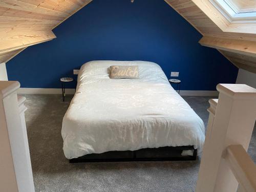 哈佛威斯特Stonecroft Cwtch的蓝色卧室,配有一张带白色棉被的床