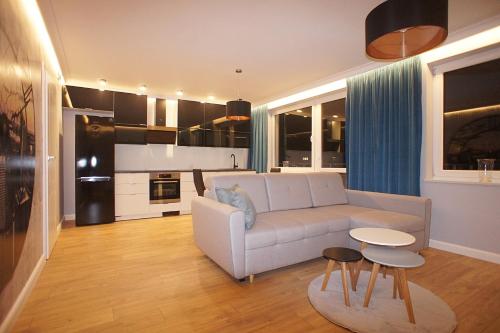 绿山城Drzewna Apartamenty -Augustowska的一间带白色沙发的客厅和一间厨房
