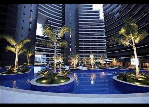 福塔莱萨Fortaleza Landscape Beira-mar: espaço inteiro的一座大型游泳池,在高楼前种有棕榈树