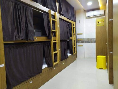 孟买Super Champions Hostel的客房设有带窗帘的两张双层床和走廊。
