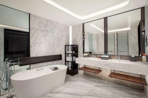 郑州郑州高新皇冠假日酒店的浴室配有两个盥洗盆和浴缸。