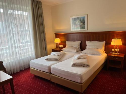 吕贝克Hotel Hanseatischer Hof的酒店客房设有两张床和两盏灯。