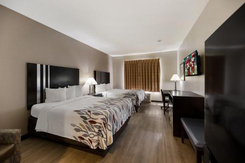 佩科斯Red Roof Inn Pecos的酒店客房设有一张大床和一张书桌。