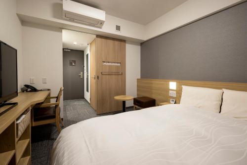 广岛Dormy Inn Hiroshima Annex的酒店客房配有一张床、一张书桌和一台电视。