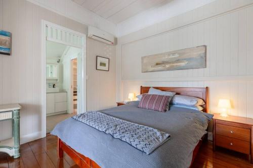 布里斯班Quaint & Cosy 1 Bedroom Apartment in Queenslander.的一间卧室配有一张带两盏灯和一个水槽的床。