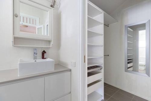 布里斯班Quaint & Cosy 1 Bedroom Apartment in Queenslander.的白色的厨房配有水槽和镜子