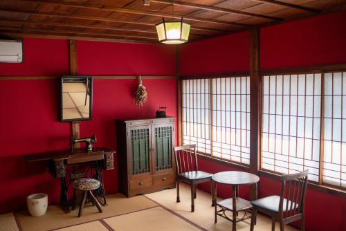 金泽Machiya Guest House Carta的一间设有红色墙壁和桌椅的房间