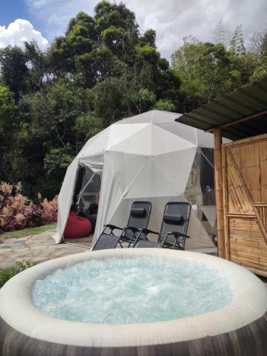 帕乔Colibamboo Domo Glamping的庭院内的热水浴池,配有椅子和帐篷