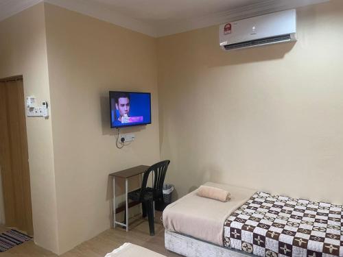 Tumpat瓦恩旅馆的卧室配有一张床,墙上配有电视。