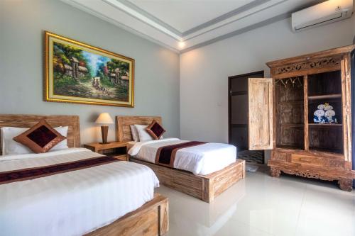 BangliAsli Bali Villas的一间卧室设有两张床,墙上挂着一幅画