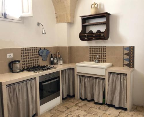 曼杜里亚Antica Casa del Pozzo的厨房配有水槽和炉灶 顶部烤箱