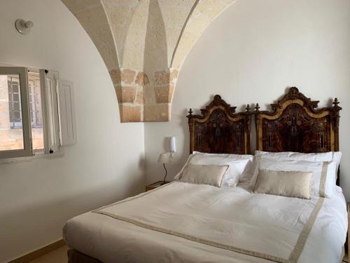 曼杜里亚Antica Casa del Pozzo的一间卧室配有一张大床和木制床头板