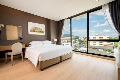 清迈Sanae' Hotel Nimman的一间卧室配有一张床、一张书桌和大窗户