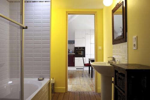 Le FaouëtLe grenier du Faouët的浴室配有黄色的墙壁、浴缸和水槽