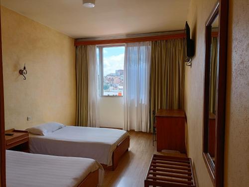 塔那那利佛Aina Hôtel的酒店客房设有两张床和窗户。