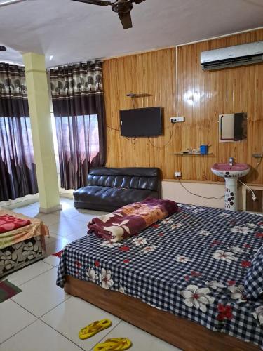JīndStacy Guest House的一间卧室配有一张床、一张沙发和一台电视。