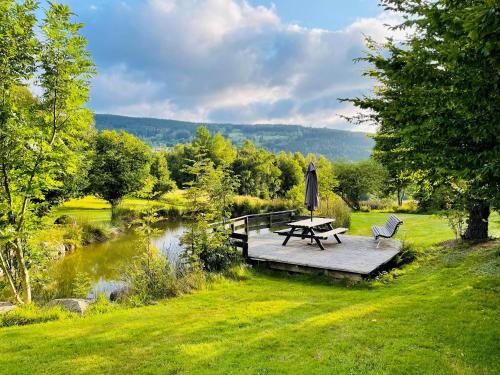克松吕-隆日梅※ Résidence POMME DE PIN - Terrasse - Nature ※的池塘旁的木甲板上摆放着野餐桌和椅子