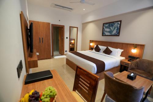 苏丹巴特利Hotel Saffron Wayanad的酒店客房,配有一张床和一张桌子,还有一碗水果
