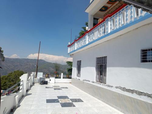 JageshwarMoonlit Heaven的一座白色建筑的阳台,其背景是群山